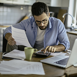 How to get out of debt in the new year - man working on finances at the kitchen table.