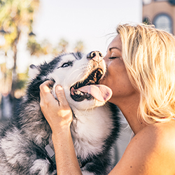 Adopt a Pet - Pretty blonde woman giving her husky a hug on a summer day.